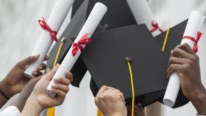 close-up-hands-holding-diplomas-caps-1-835827948